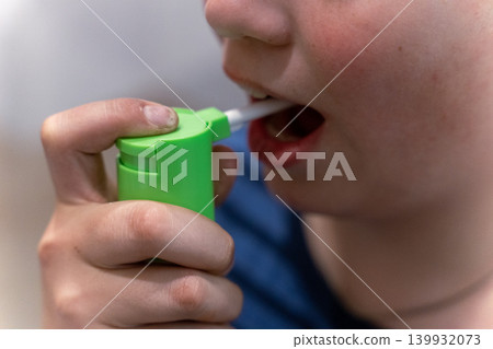 Child uses green inhaler to take medication indoors during a health routine Child uses green inhaler to take medication indoors during a health routine 139932073