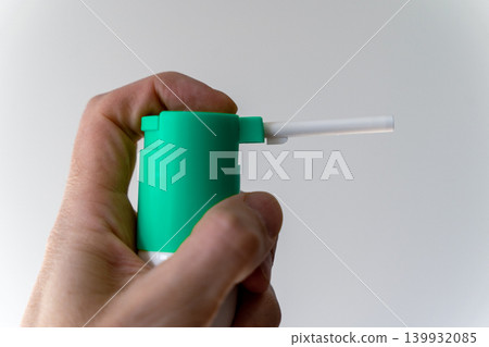 Hand holds green spray can with nozzle pointing forward, ready for use in a simple space 139932085