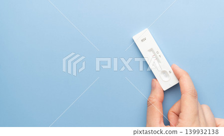 Woman hands holding Respiratory Syncytial Virus (RSV) antigen rapid test kit with positive result on blue background. 139932138