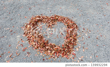 close up of a heart shape made of autumn leaves in red, orange and brown on the gravel ground close up of a heart shape made of autumn leaves in red, orange and brown on the gravel ground 139932294