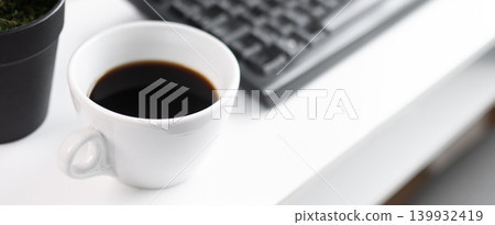 Black Coffee Cup on Minimal White Desk with Keyboard and Plant Black Coffee Cup on Minimal White Desk with Keyboard and Plant 139932419