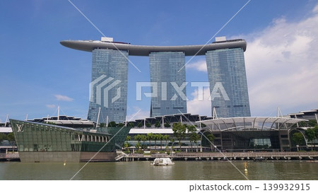 Marina Bay Sands stands tall against the blue sky, and the futuristic glass architecture appears to float on the water. Marina Bay Sands stands tall against the blue sky, and the futuristic glass architecture appears to float on the water. 139932915