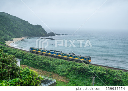 一列山陰本線的特快列車在雨中沿著日本海沿岸行駛。 一列山陰本線的特快列車在雨中沿著日本海沿岸行駛。 139933354