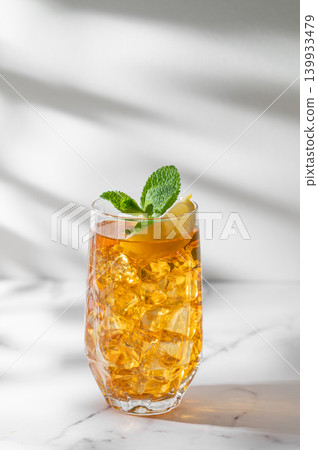Iced tea with lemon and mint in a glass on a marble background with shadows. 139933479