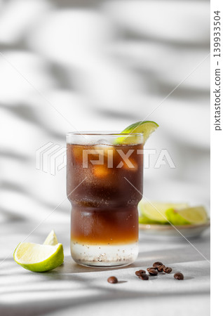 Cold Coffee Tonic Drink With Lime and Ice on light background with shadows 139933504