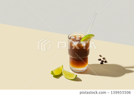 Cold Coffee Tonic Drink With Lime and Ice on light background with shadows Cold Coffee Tonic Drink With Lime and Ice on light background with shadows 139933506