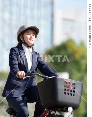 A young businesswoman traveling by bicycle in an urban area. A young businesswoman traveling by bicycle in an urban area. 139933744
