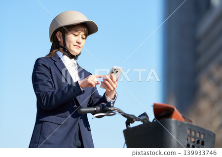 A female office worker using her smartphone while cycling A female office worker using her smartphone while cycling 139933746
