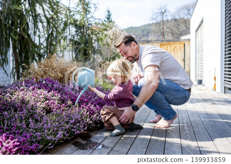 Father and son watering plants together in garden. Father and son watering plants together in garden. 139933859