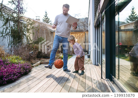 Father controlling smart home exterior blinds using tablet while standing with toddler son. 139933870