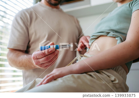 Dad assisting diabetic teen girl with daily insulin treatment routine. 139933875