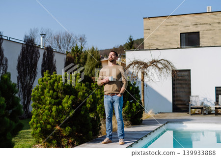Relaxed man drinking coffee on terrace at home on sunny day. 139933888