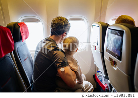 Father taking care of toddler during family flight. Father taking care of toddler during family flight. 139933891