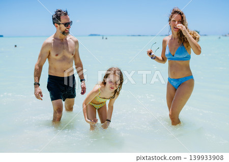 Happy family with daughter playing together in shallow tropical sea water during summer vacation. Happy family with daughter playing together in shallow tropical sea water during summer vacation. 139933908