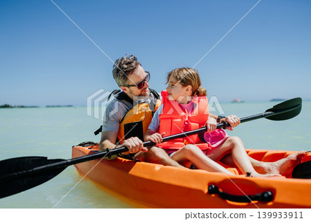 Father kayaking with daughter on calm sea during family summer vacation. Father kayaking with daughter on calm sea during family summer vacation. 139933911