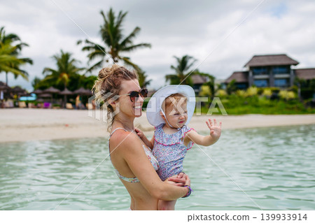 Mother playing in sea water with little daughter. Mother playing in sea water with little daughter. 139933914