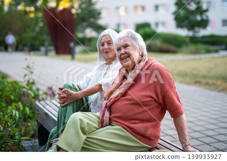 Elderly mother sitting on bench with adult daughter. 139933927