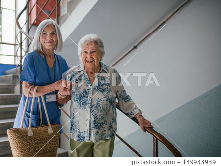 Female healthcare worker helping senior patient walking down the stairs. 139933939