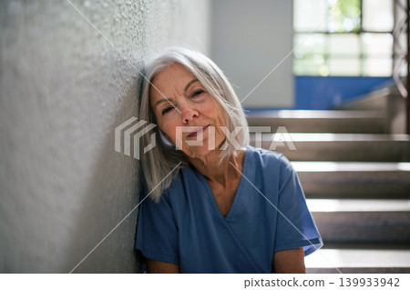 Senior nurse resting on stairwell during hospital shift Senior nurse resting on stairwell during hospital shift 139933942