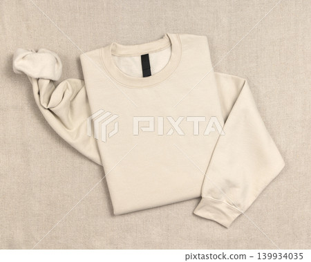 Blank beige unisex sweatshirt mockup, folded crewneck flat lay with copy space on front and sleeve Blank beige unisex sweatshirt mockup, folded crewneck flat lay with copy space on front and sleeve 139934035