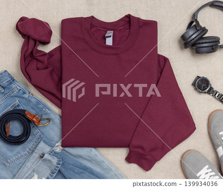 Blank dark red unisex sweatshirt mockup, folded crewneck with denim jeans and mens accessories Blank dark red unisex sweatshirt mockup, folded crewneck with denim jeans and mens accessories 139934036