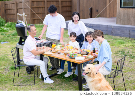 A family and their dog enjoying a barbecue in the garden. A family and their dog enjoying a barbecue in the garden. 139934126