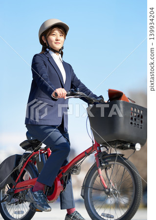 A young woman riding an electric bicycle while wearing a helmet A young woman riding an electric bicycle while wearing a helmet 139934204