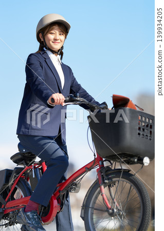 A young woman riding an electric bicycle while wearing a helmet A young woman riding an electric bicycle while wearing a helmet 139934205