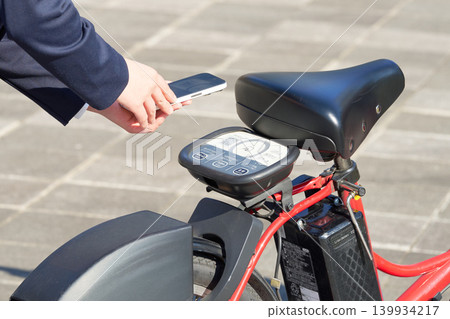 一名女子使用智慧型手機驗證的共享單車時,雙手在車內。 一名女子使用智慧型手機驗證的共享單車時,雙手在車內。 139934217