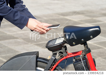 一名女子使用智慧型手機驗證的共享單車時,雙手在車內。 一名女子使用智慧型手機驗證的共享單車時,雙手在車內。 139934218