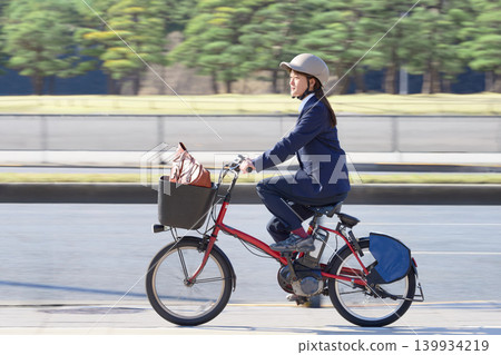一名女上班族戴著頭盔,騎著電動自行車上下班。 一名女上班族戴著頭盔,騎著電動自行車上下班。 139934219