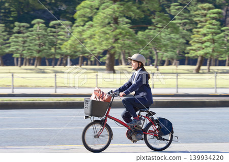 一名女上班族戴著頭盔,騎著電動自行車上下班。 一名女上班族戴著頭盔,騎著電動自行車上下班。 139934220