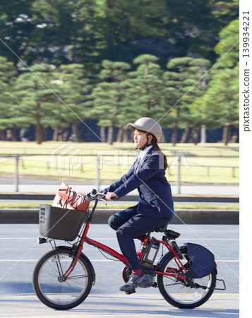 A businesswoman traveling around the city on an electric bicycle. A businesswoman traveling around the city on an electric bicycle. 139934221