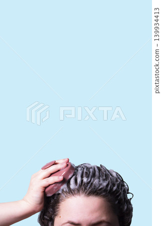 Hair brush for stimulating hair growth on blue background. Microcirculation, help to distribute natural oils more evenly across the scalp Hair brush for stimulating hair growth on blue background. Microcirculation, help to distribute natural oils more evenly across the scalp 139934413