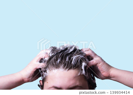 Woman Washing her hair with shampoo foam isolated on blue background. Symbol of hair care. Treatment and health related theme. 139934414