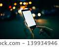 Nighttime smartphone use in a busy cityscape 139934946