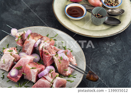 Uncooked pork kebabs with onion on skewers Uncooked pork kebabs with onion on skewers 139935012