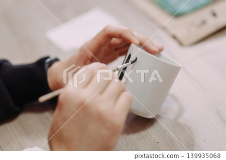Man painting handmade ceramic cup at workshop Man painting handmade ceramic cup at workshop 139935068