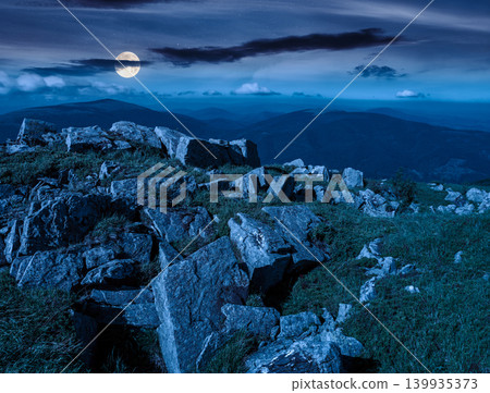 mountain landscape with stones and grass at night. mysterious view of carpthian mountains in summer. full moon over white sharp stones on the rolling hills on top of mountain range under dark sky 139935373