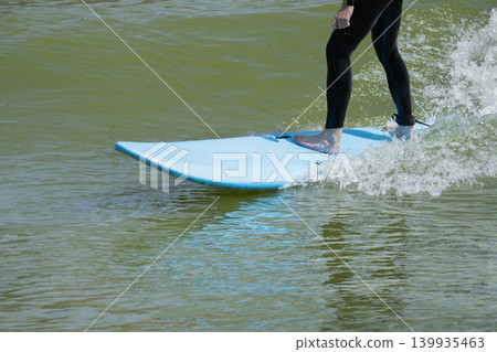 Action shot of a surfer riding an wave on a bodyboard with splashing white water on a sunny day. Action shot of a surfer riding an wave on a bodyboard with splashing white water on a sunny day. 139935463