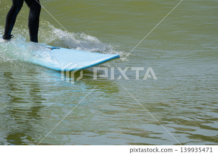Action shot of a surfer riding an wave on a bodyboard with splashing white water on a sunny day. 139935471