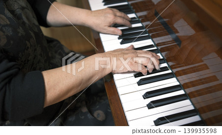 The elderly hands of a professional pianist on the piano keys, close-up. A woman is playing the piano. Music school. The concept of creativity, inspiration and art The elderly hands of a professional pianist on the piano keys, close-up. A woman is playing the piano. Music school. The concept of creativity, inspiration and art 139935598