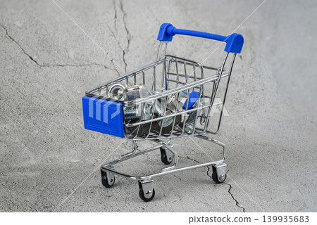 bolts and nuts in a shopping cart on a concrete gray background. bolts and nuts in a shopping cart on a concrete gray background. 139935683