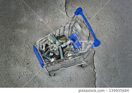 bolts and nuts in a shopping cart on a concrete gray background. bolts and nuts in a shopping cart on a concrete gray background. 139935684