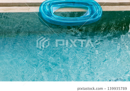 Top view closeup of turquoise inflatable ring floating on swimming pool water surface. Top view closeup of turquoise inflatable ring floating on swimming pool water surface. 139935789