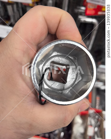 Hand holding a shiny socket tool in a hardware store aisle Hand holding a shiny socket tool in a hardware store aisle 139935838