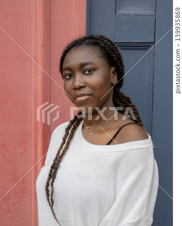 Young African woman portrait against pink and blue wall, urban lifestyle Young African woman portrait against pink and blue wall, urban lifestyle 139935869