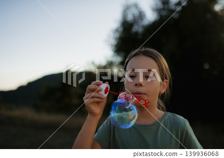 Little girl blowing soap bubbles in nature during sunny spring day. 139936068