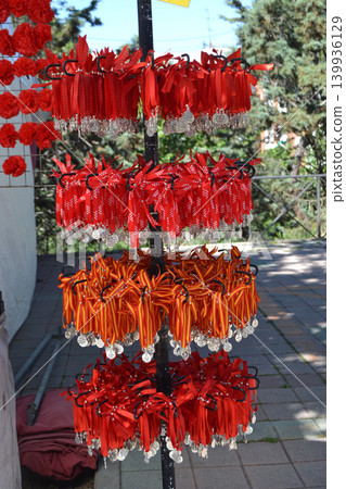 Multiple tiers of red and yellow ribbon medallions displayed on a rack at san isidro fair for souvenir shoppers and festival decoration background 139936129