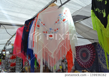Embroidered floral shawls with long fringe hanging at madrid san isidro fair for textile display and decorative market background Embroidered floral shawls with long fringe hanging at madrid san isidro fair for textile display and decorative market background 139936162